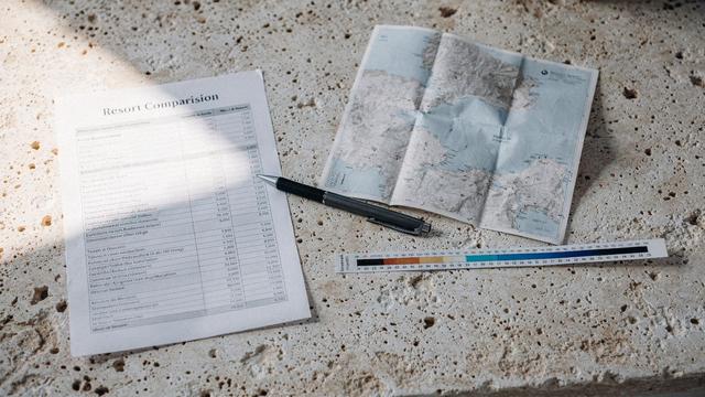 Printed resort comparison sheet on a desk beside a folded map and a pen